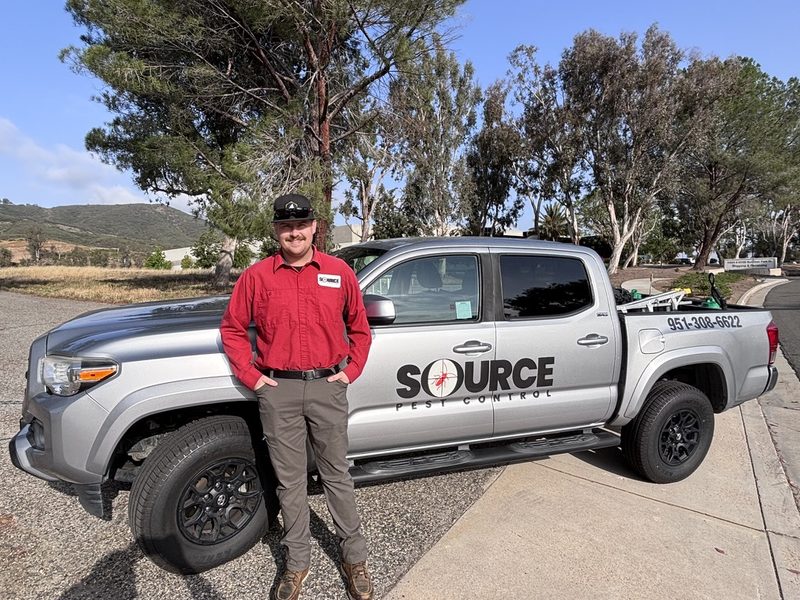 A licensed Source Pest Control technician by the service truck